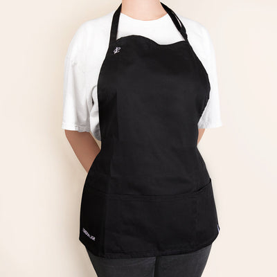 a simple black apron for lash techs, featuring a front pocket and a small london lash logo on the right breast