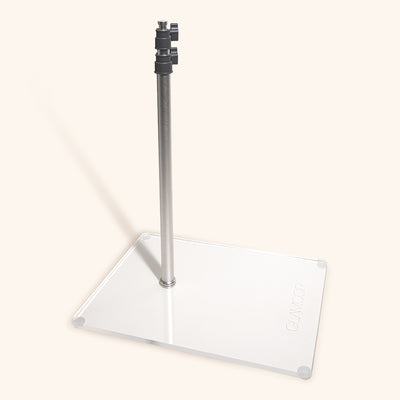 the glamcor flat base stand with the pole screwed in. the base is white with a shiny clear covering and the pole is matte silver. The adjustable part of the pole is shown at the top, but the pole is not extended
