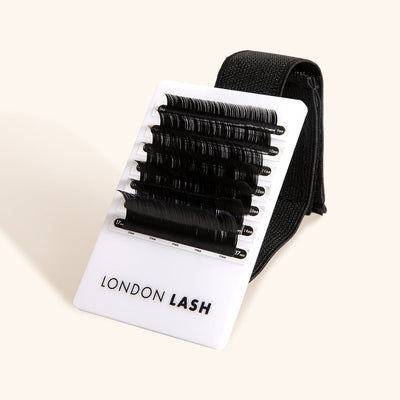 a small lash tile resting against its wrist strap. there are seven strips of lashes on the palette