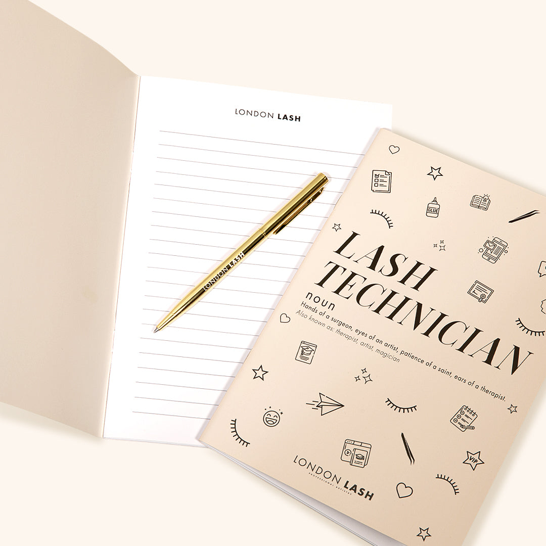 Writing in a Lash Technician notebook with a branded gold pen