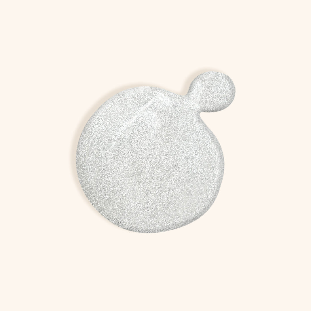 Shimmery pearl white nail polish in front of a beige background