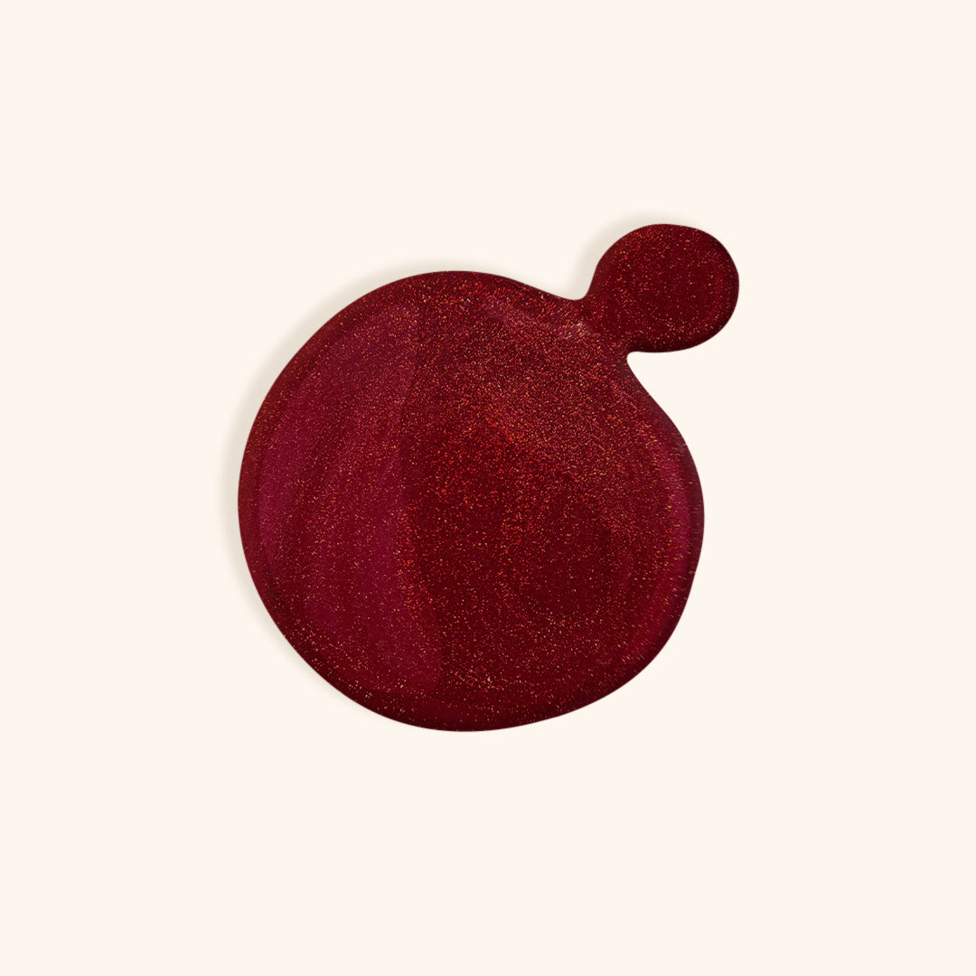 Ruby red nail polish color in front of a beige background