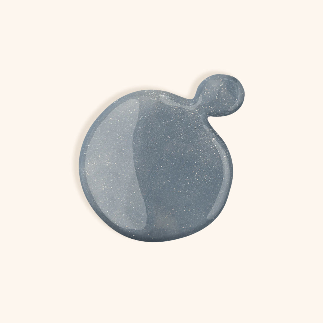 Glittery denim blue nail polish with turquoise hue in white bottle