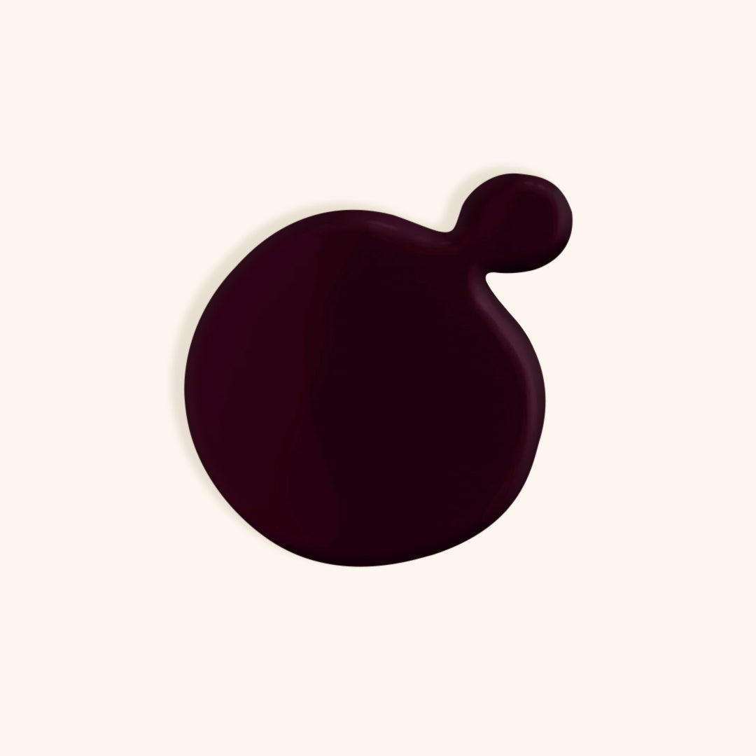 Extreme dark purple nail polish in front of a beige background