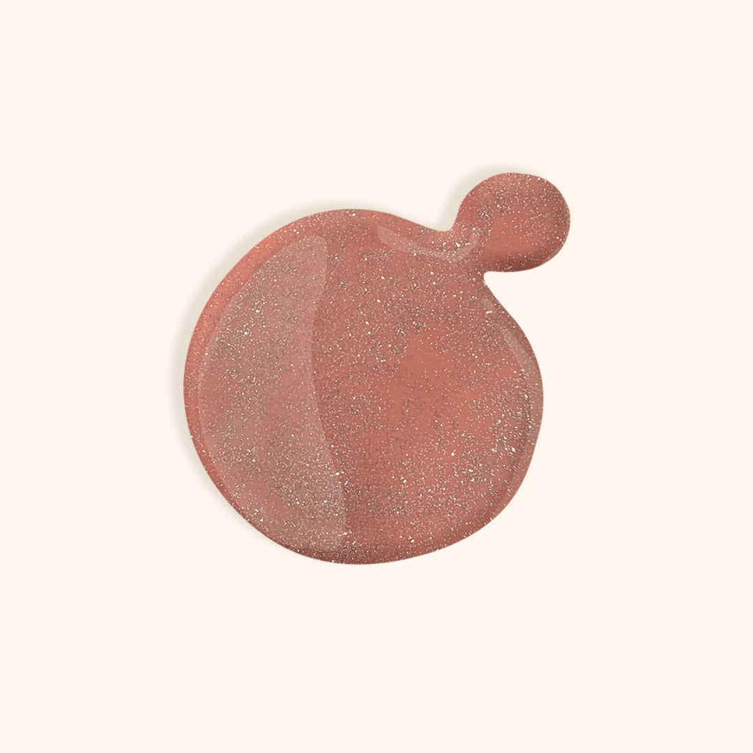 Deep shimmery pink nail polish in front of a beige background