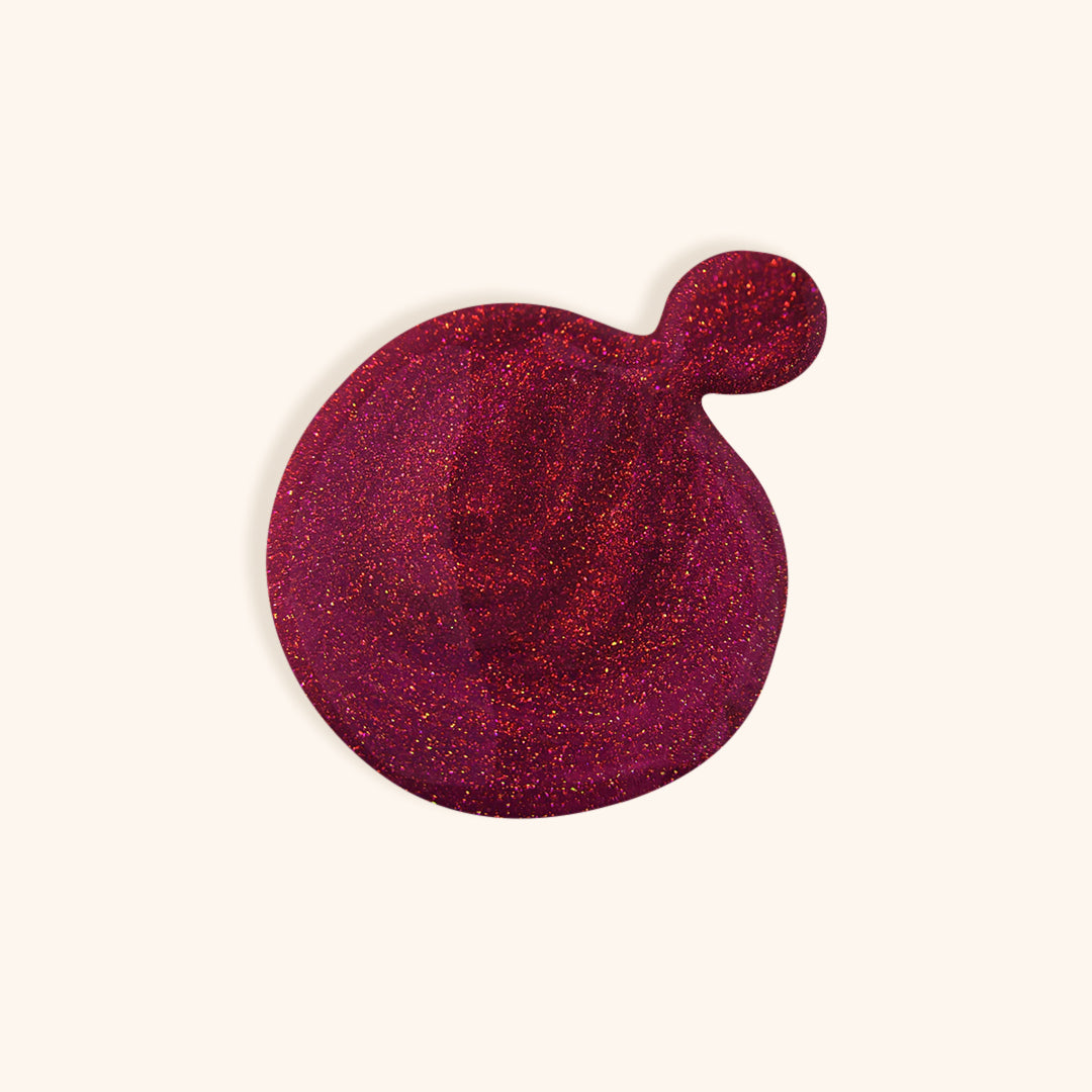 Dark red nail polish with shimmer in a white bottle