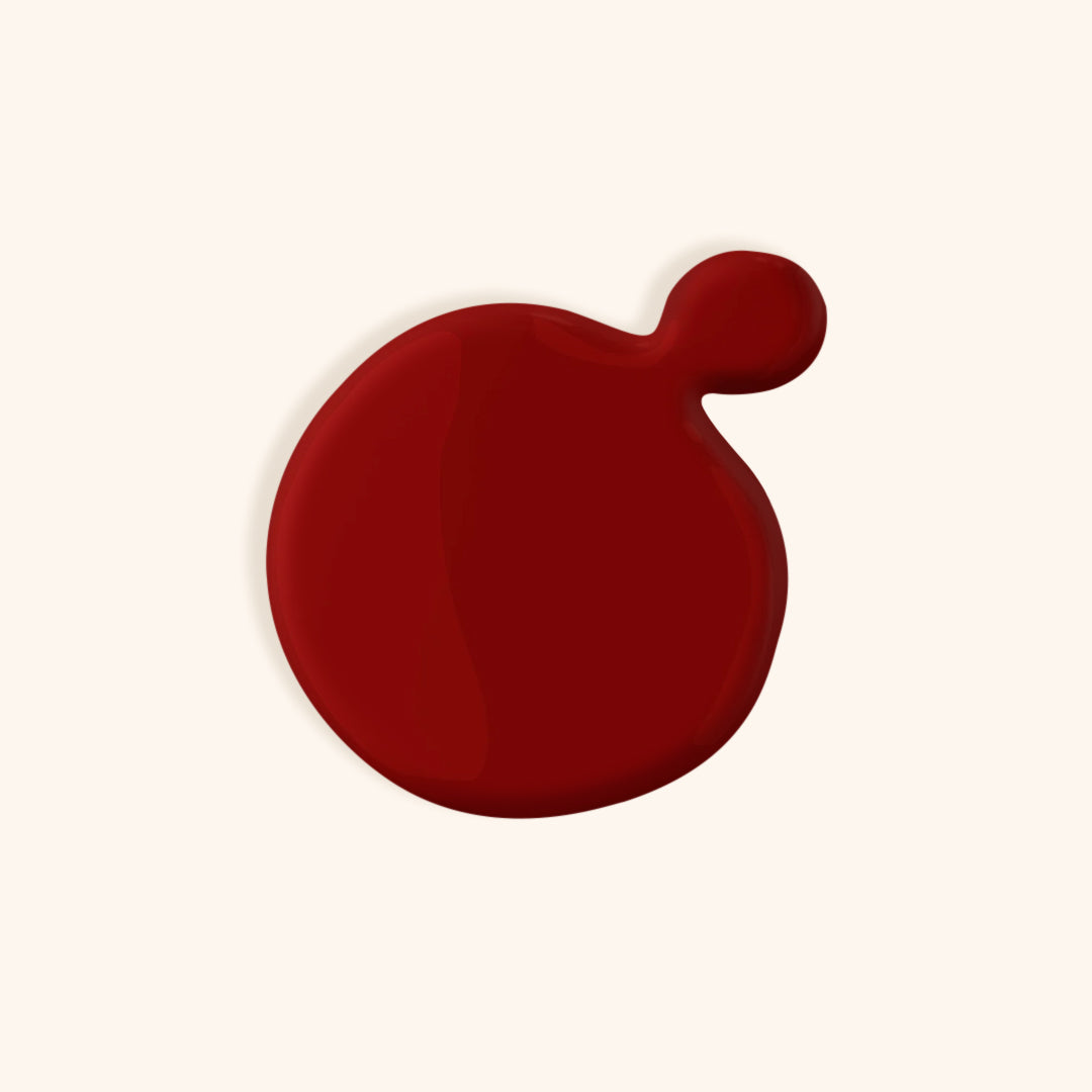 Bright deep red nail polish color in front of a beige background