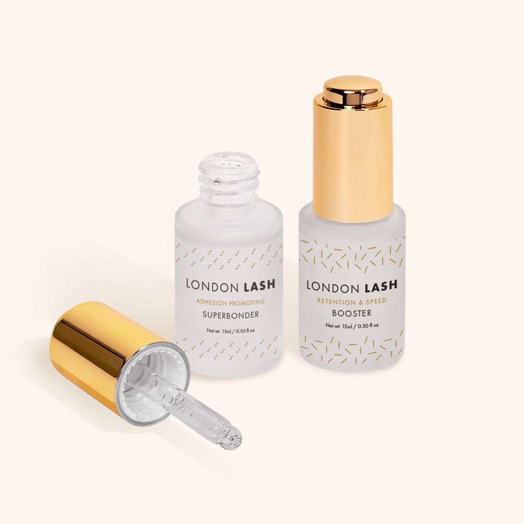 an open bottle of london lash superbonder next to a bottle of london lash booster. the superbonder lid lays to the side of the open bottle showing the glass pipette