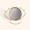 a gold eye shaped mirror with a stand