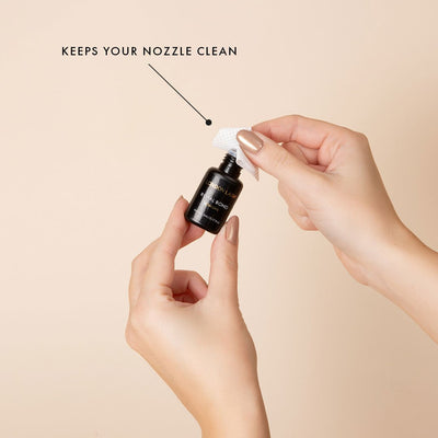 one hand holds a bottle of lash glue while the other hand is using a glue nozzle wipe to keep the nozzle clean. there is an informational notes that the wipes keep your nozzle clean