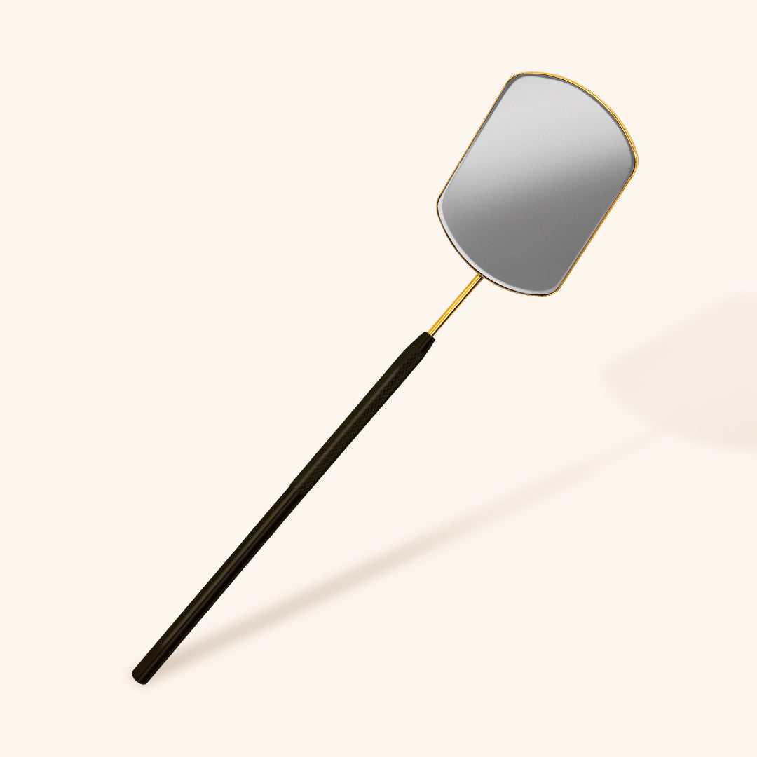 a lash mirror with a black metal handle and gold frame