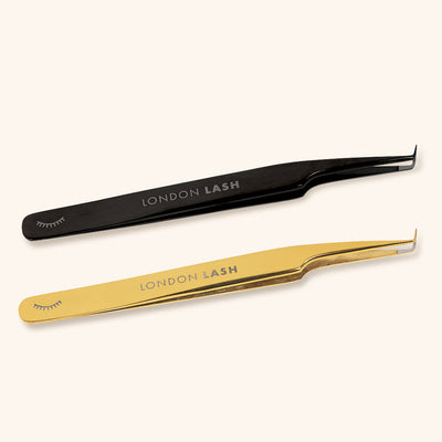 mega volume lash tweezers with ultra fine tips and fiber grip. A pair of black tweezers and a pair of gold lay side by side.