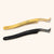 mega volume lash tweezers with a wide tip and fiber grip. A pair of black tweezers and a pair of gold lay side by side.