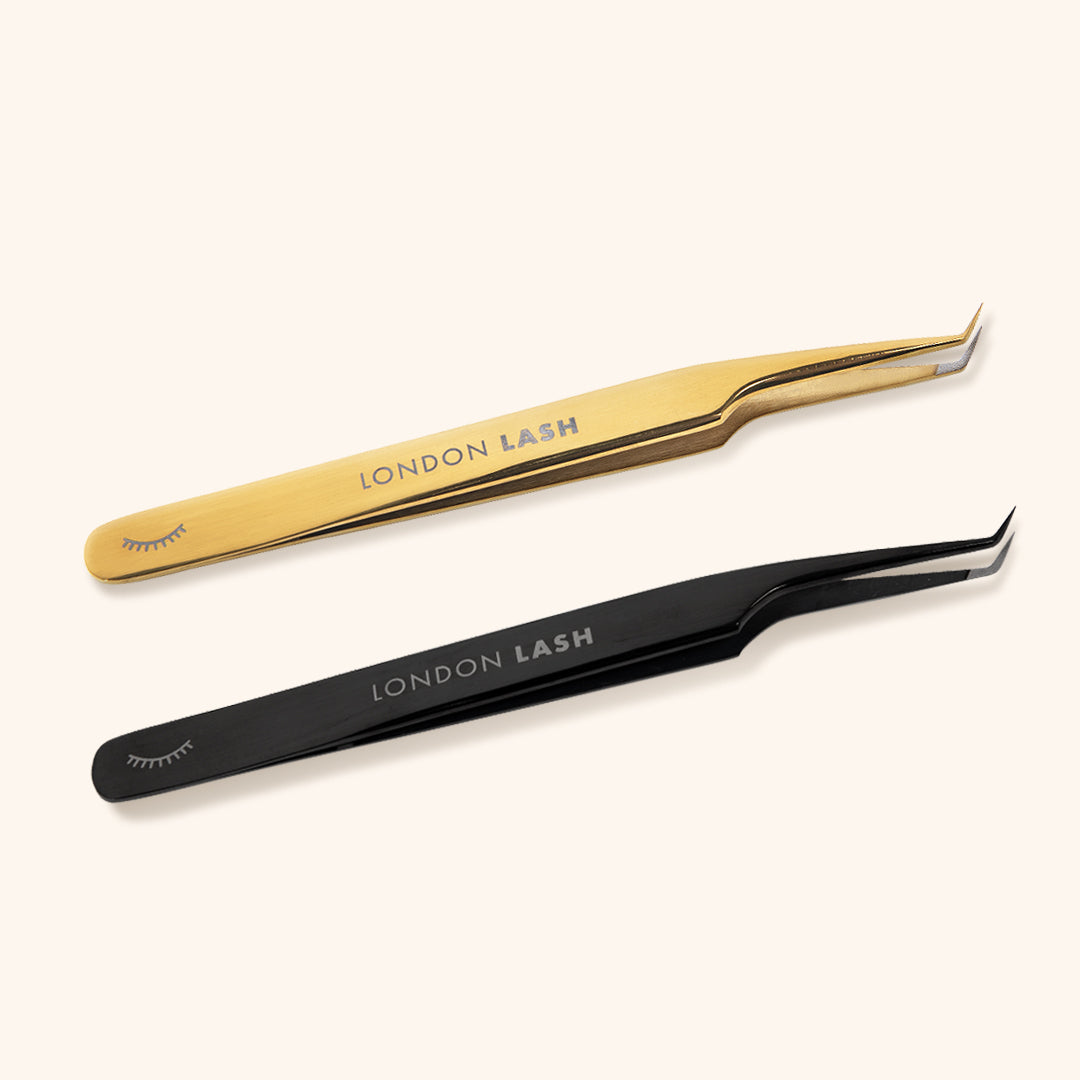 mega volume lash tweezers with a long slim tip and fiber grip. A pair of black tweezers and a pair of gold lay side by side.