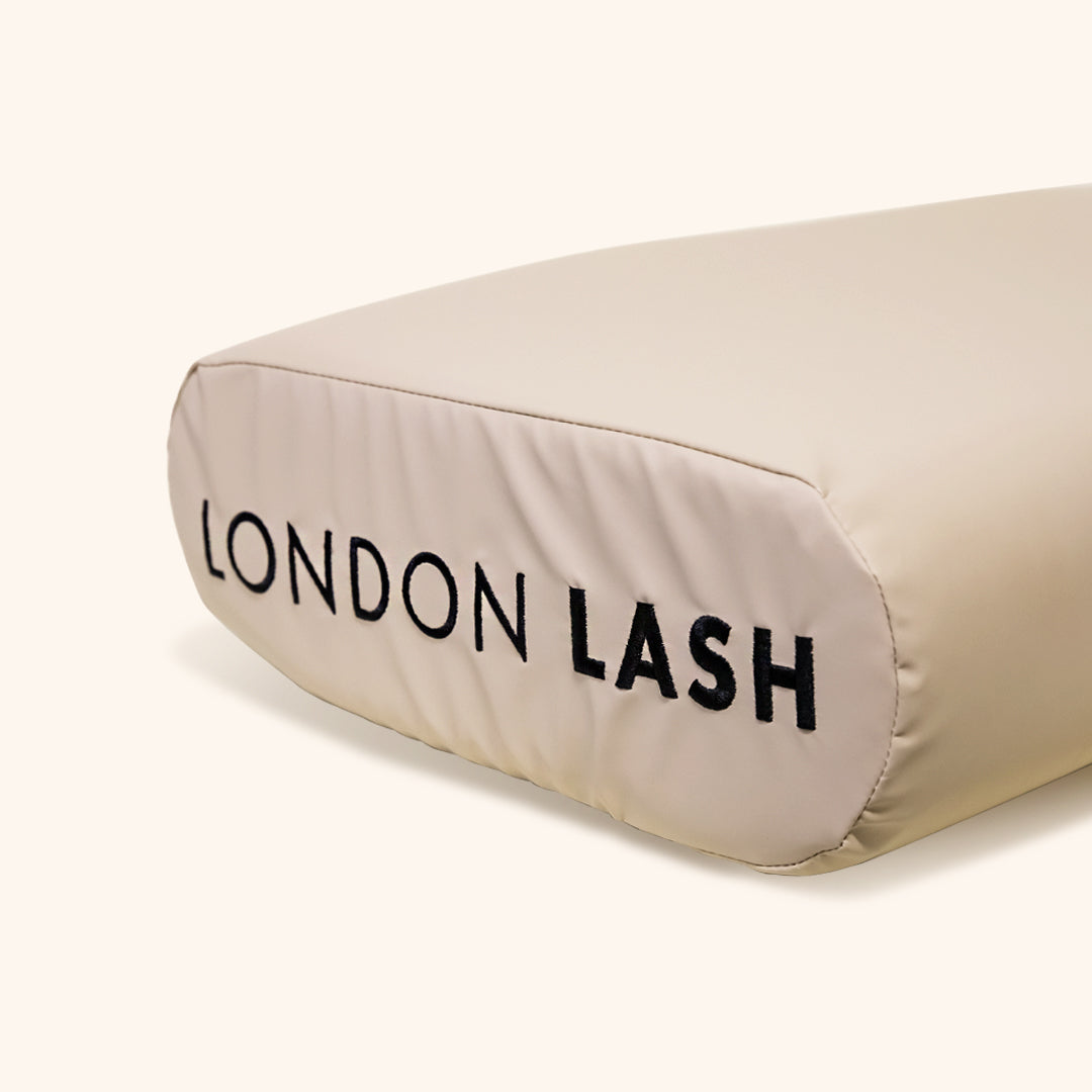 a close up of the london lash logo on the end of the beige memory foam neck pillow 