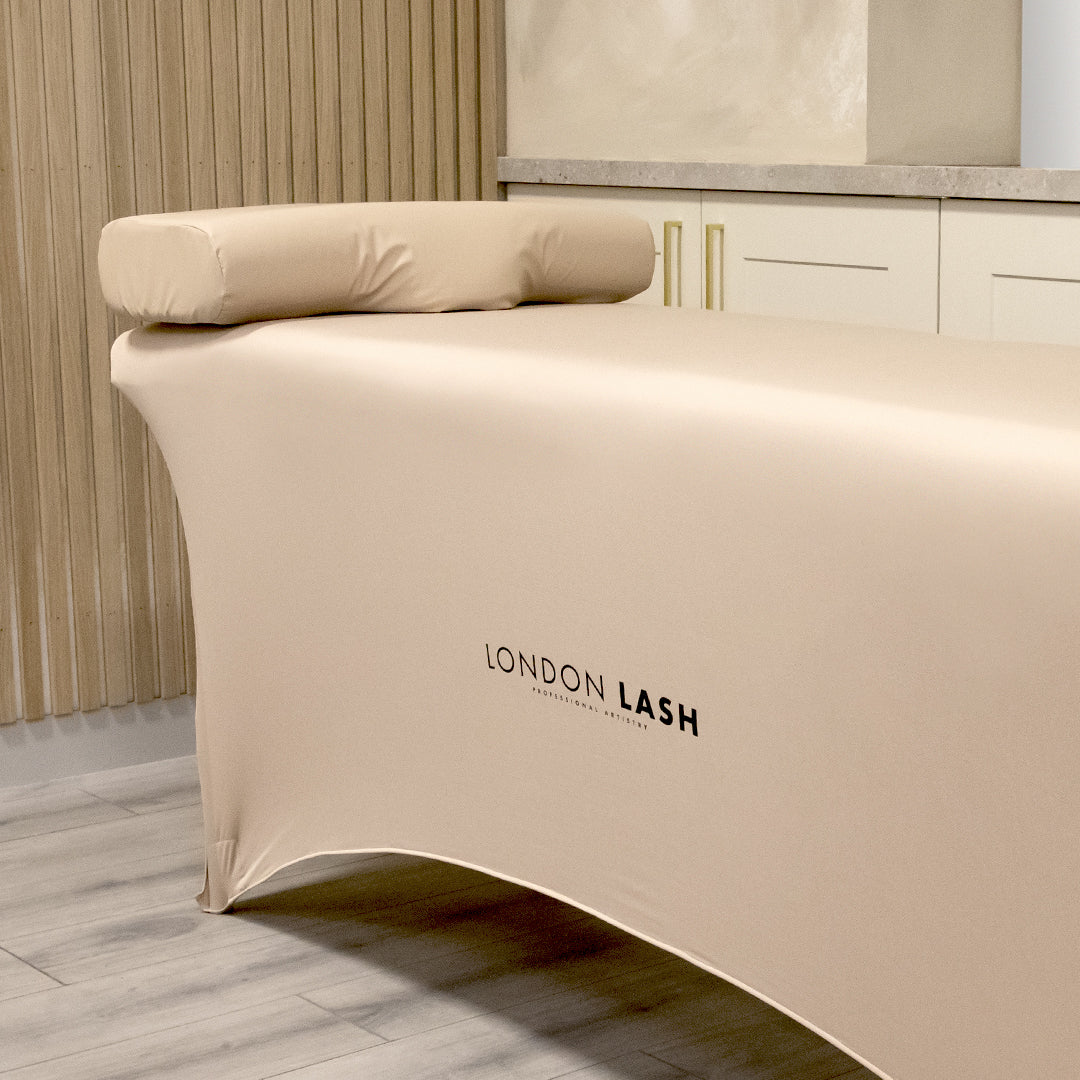 a beauty bed in a salon with a beige bed cover and matching memory foam neck pillow