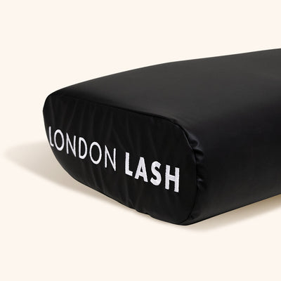 a close up of the london lash logo on the end of the black memory foam neck pillow