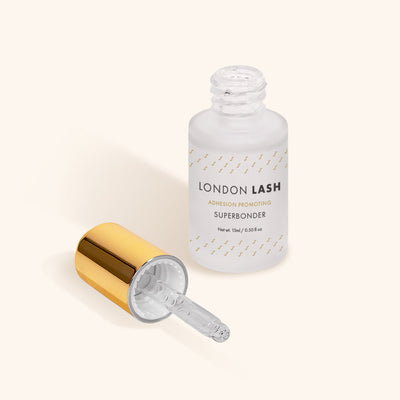 a bottle of london lash superbonder lash glue sealant with the lid laying next to it to show the pipette